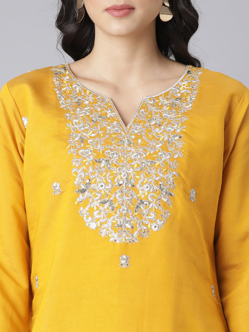 Yellow kurta with silver embroidery on the neckline against a gray background.