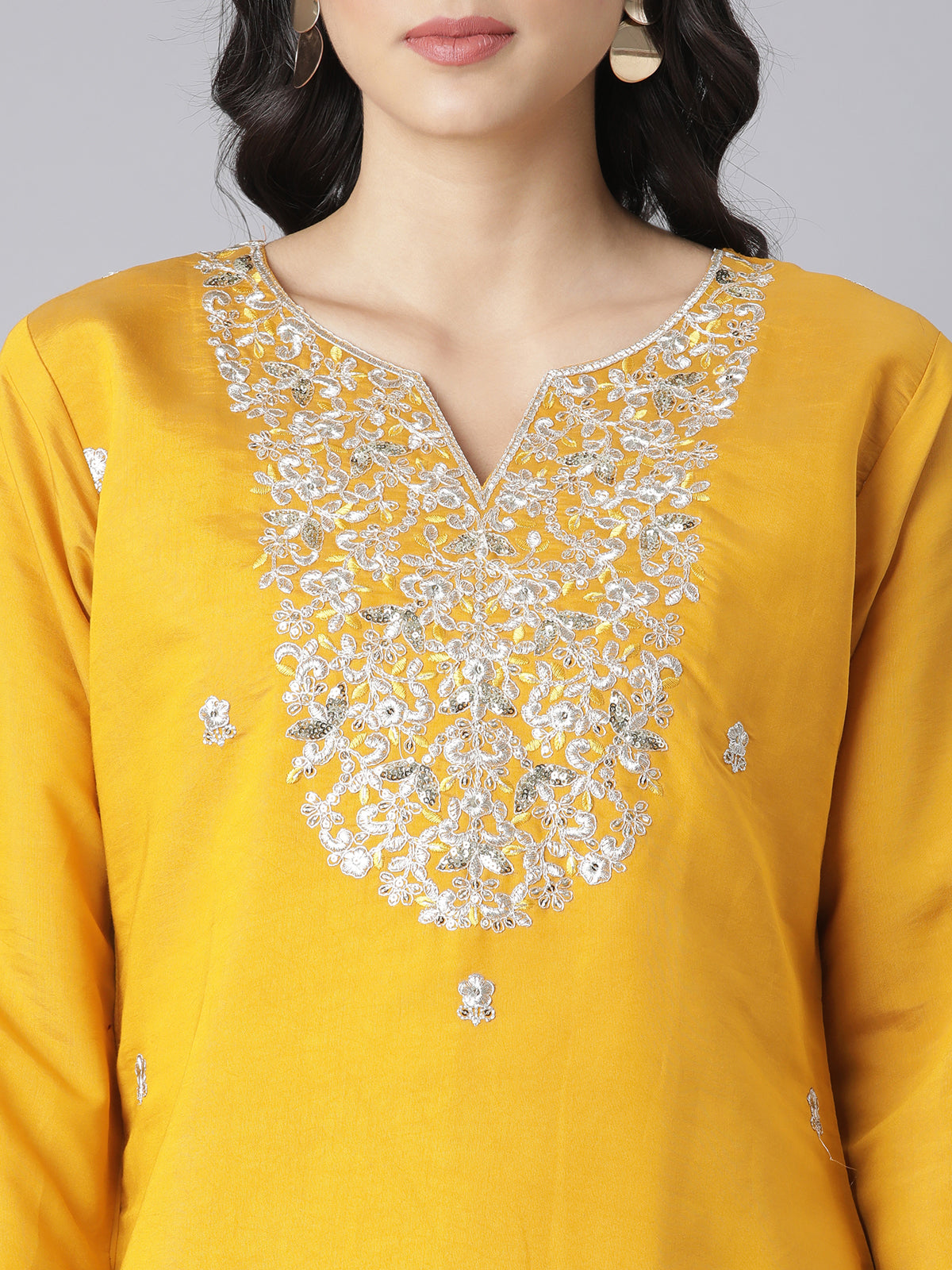 Yellow kurta with silver embroidery on the neckline against a gray background.